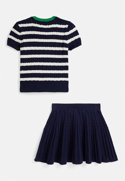 Námornícka modrá pletená krátkym rukávom so sivými pásmi a zeleným golierom, skombinovaná so skladanou námorníckou modrou sukňou s textúrovaným vzorom.