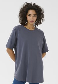 T-shirt grigio oversize con maniche raglan corte, scollo rotondo e texture liscia. Progettato per una vestibilità rilassata, arriva sotto i fianchi.