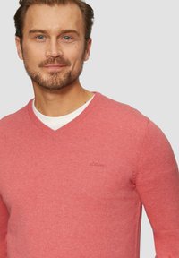 Różowy sweter w serek o gładkiej strukturze, z delikatnym logo s.Oliver na piersi. Posiada długie rękawy i luźny krój.