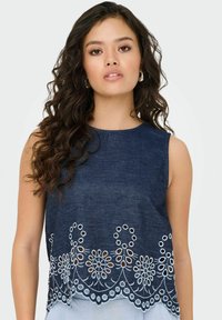 Top senza maniche in denim caratterizzato da un intricato ricamo in pizzo floreale bianco lungo l'orlo, con scollatura tonda e vestibilità comoda.