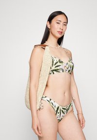 Conjunto de biquíni com um padrão tropical de folhas de palmeira em verdes e rosas, com alças finas ajustáveis e um fundo com laço à lateral combinando.