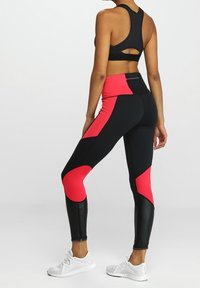 Set di abbigliamento attivo nero e rosa composto da un top corto con schiena a racer e leggings a vita alta con un design a blocchi di colore geometrico e accenti testurizzati.