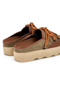 Scarpe marroni e beige con tomaia in suede, lacci arancioni e una spessa suola piattaformas beige ondulata. Presentano un design con punta arrotondata.
