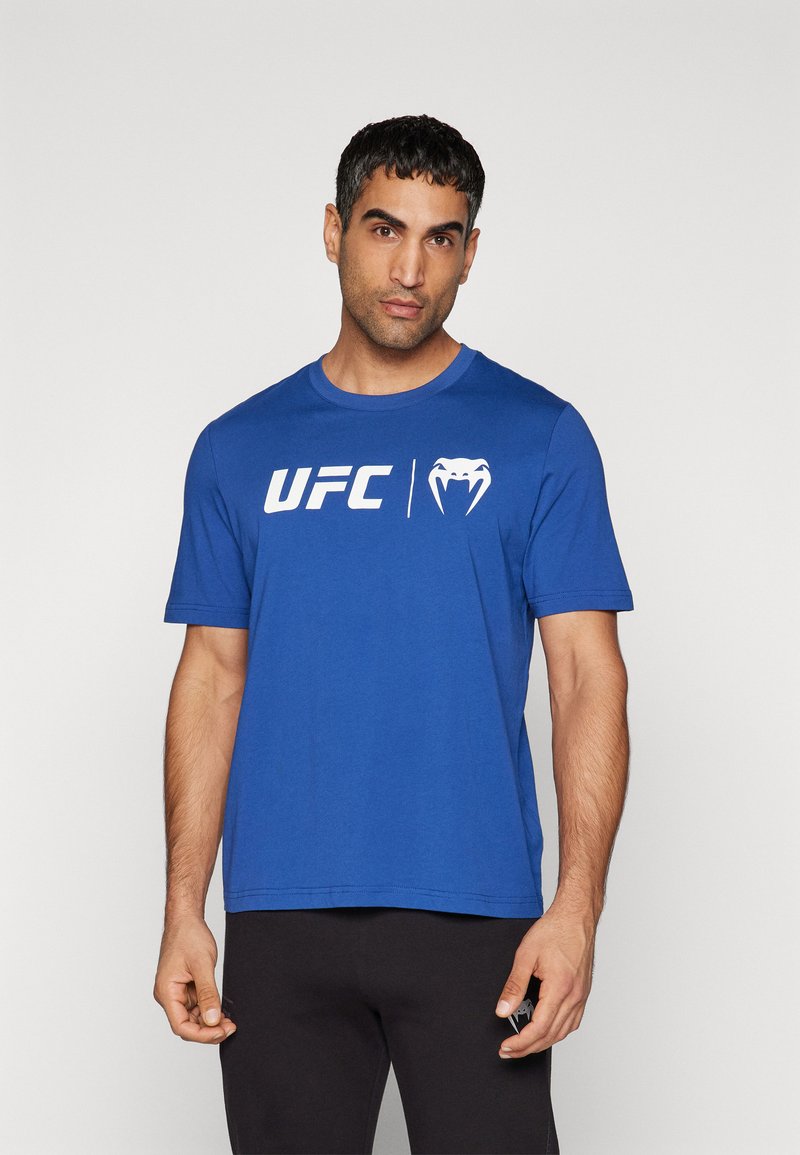 Blå bomulds t-shirt med iøjnefaldende hvid "UFC" logo og grafik på fronten. Rund halsudskæring og korte ærmer med en afslappet pasform.