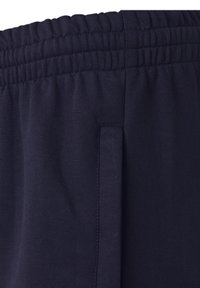 Närbild av ett mörkblått elastiskt midjeband och sidofickan på ett par avslappnade sweatpants.