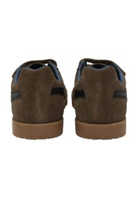 Zapatos de ante marrón con un acabado texturizado, acentos negros en los laterales y una suela de goma. Presentan una parte trasera redondeada y un interior acolchado.