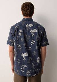 Kurzärmeliges Hemd in Dunkelblau mit weißem Blumenmuster, aus strukturiertem Stoff, mit weichem Kragen und abgerundetem Saum. Standard-Passform.