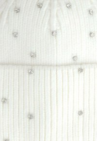 Berretto lavorato a maglia bianco con texture a coste, decorato con piccole borchie argentate sparse. Materiale morbido con vestibilità aderente.