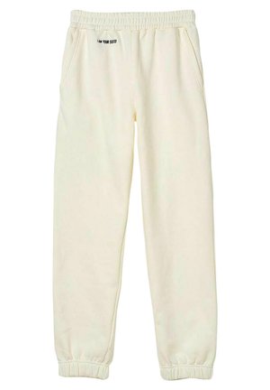 Világos krémszínű, puha anyagból készült melegítőnadrág, rugalmas derékkal és mandzsettával, oldalsó zsebekkel, és hímzett "ÉN VAGYOK A HUGOD" felirattal.