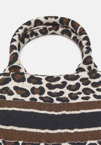 Sac fourre-tout imprimé léopard avec une texture douce, présentant des rayures marron foncé, noires et crème, et des poignées arrondies pour un transport facile.