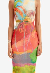 Tætsiddende kjole med et farverigt palmetræsbillede i nuancer af pink, rød, orange og grøn på et glat stof. Sølv armbånd som tilbehør.