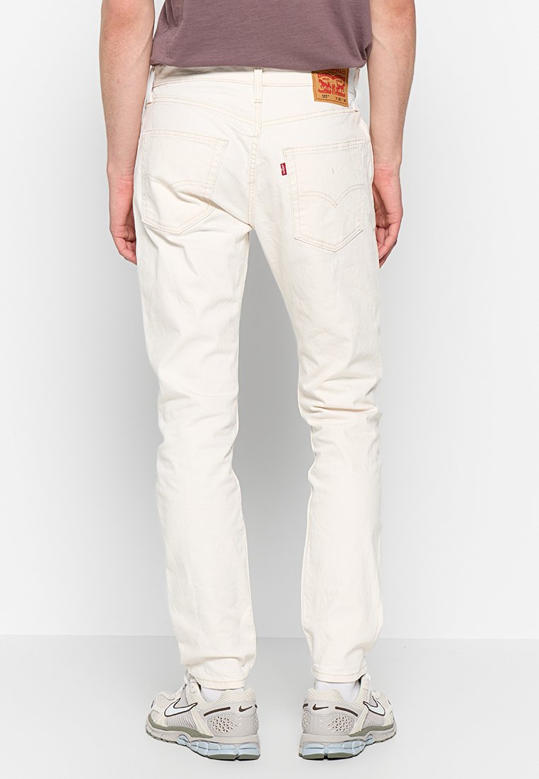 Weiße Jeans im Slim-Fit mit aufgesetzten Gesäßtaschen, subtilen Stickdetails und einem Markenschild am Bund.