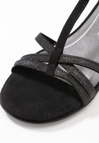 Schwarze High-Heel-Sandalen mit Wildleder- und Glitzer-Riemen, ausgestattet mit einer glatten Innensohle und offenen Zehen.