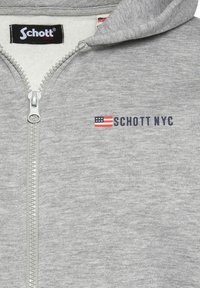 Felpa grigia con zip realizzata in pile con una consistenza morbida. Caratterizzata da una zip frontale, cappuccio e un logo con design della bandiera americana.