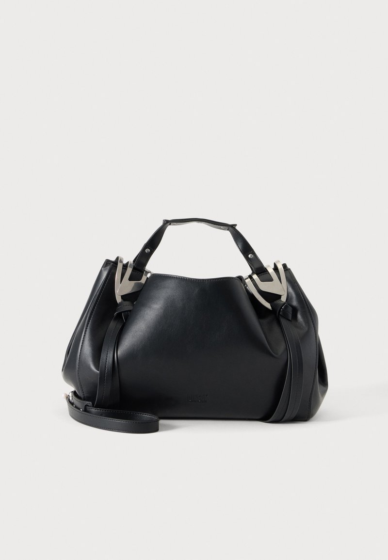 Sac à main en cuir noir avec des accents métalliques argentés en forme de V, deux poignées supérieures et une bandoulière amovible sur un fond clair uni.