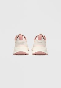 Sneakers Calvin Klein in rosa chiaro e beige. Presentano una suola bianca spessa, un'impugnatura sul retro e un branding discreto sul tallone.