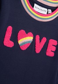 Marineblaues T-Shirt mit strukturiertem pinken "LOVE" Schriftzug, einer Herzform und mehrfarbigem gestreiften Detail. Runde, gerippte Kragen.