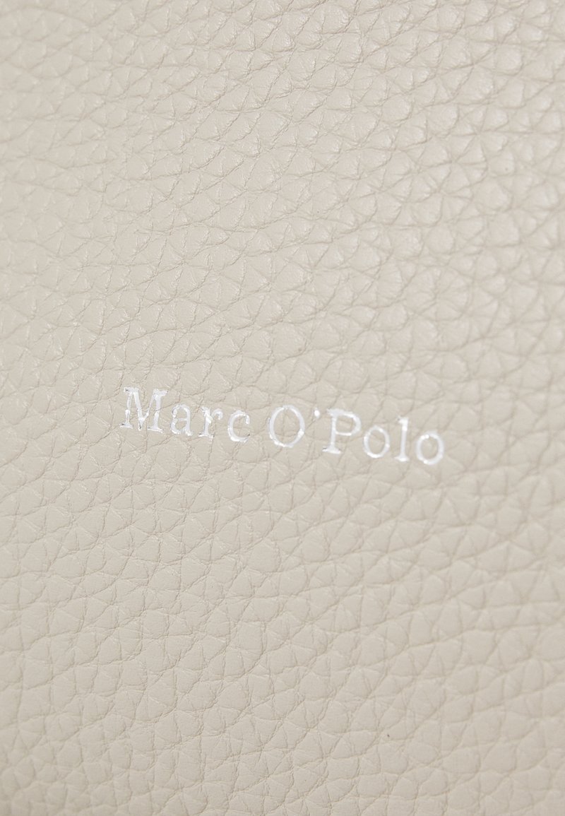 Beżowa skórzana tekstura z wytłoczonym logo "Mare O'Polo" w białym kolorze. Powierzchnia wykazuje subtelny wzór ziarna.