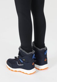 Marineblaue Winterstiefel mit grauem Fleece-Futter, verstellbaren Riemen und orangefarbener Gummisohle. Sie verfügen über ein strukturiertes Material und ein unterstützendes Design.