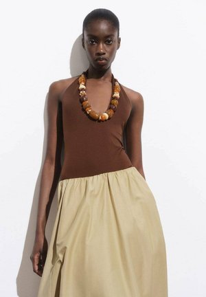 Hnědý halter top s béžovou sukní, doplněný masivním náhrdelníkem z vícebarevných korálků. Hladká tkanina s nařaseným pasem.