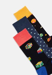 Drei Paar bunte Socken: schwarz mit Rubik's Cube-Muster, navy mit Punkten und leuchtend gelbe, blaue und korallenfarbene Bündchen. Weiches Material.