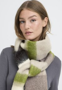 Écharpe en mélange de laine dans des teintes douces de vert, crème et gris, avec une surface texturée ornée de motifs géométriques.