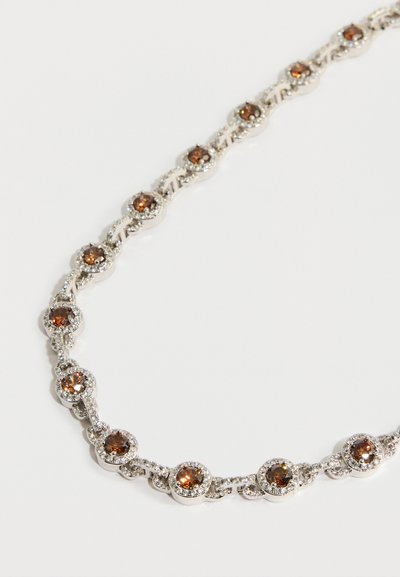 Srebrnkasta ogrlica z izmenjujočimi se okroglimi rjavimi kamni, obdana z majhnimi prozornimi kamni, z zasukano obliko verige.