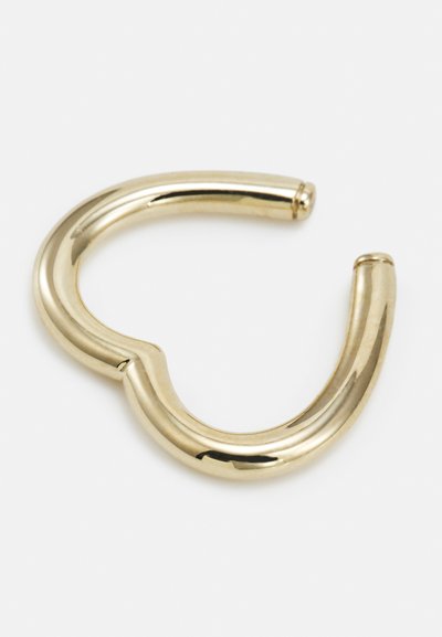 Anello in metallo color oro con un design liscio e ondulato. Presenta bordi arrotondati e una piccola apertura, riflettendo la luce con una finitura lucida.