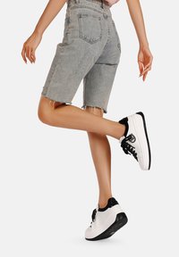 Shorts in denim grigio con orlo sfrangiato, caratterizzati da una vita alta e tasche posteriori, abbinati a sneakers bianco e nero.