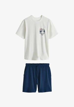 Bílé tričko s krátkým rukávem s emblémem Felixe kocoura spojené s tmavě modrými šortkami s elastickým pasem.