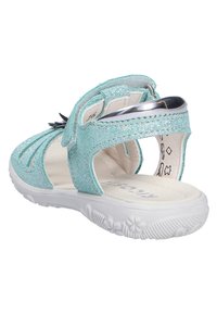 Türkise, glitzernde Sandale für Kinder mit weißer, gepolsterter Sohle, verstellbarem Riemen und blütenförmigem Profilmuster auf der Unterseite.