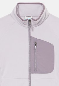 Veste en polaire violet clair avec un col montant, une fermeture éclair à l'avant et une poche sur la poitrine d'une teinte plus foncée de violet. Dotée d'une texture lisse.