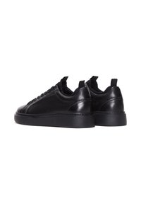 Un paio di sneakers basse in pelle nera con suole in gomma nera, cuciture visibili e linguette, su sfondo bianco.