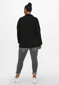 Musta pitkähihainen yläosa kauluksella, yhdistetty harmaisiin revittyihin kapeisiin farkkuihin ja valkoisiin tennareihin. Teksturoidusta kankaasta valmistettu väljä istuvuus.