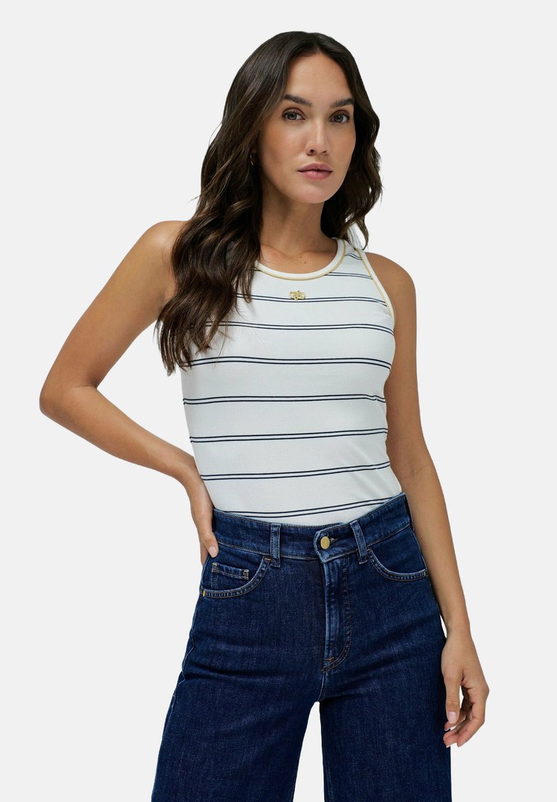 Top blanco sin mangas con rayas horizontales en azul marino, con una textura acanalada y un escote redondeado, combinado con unos jeans oscuros de tiro alto.