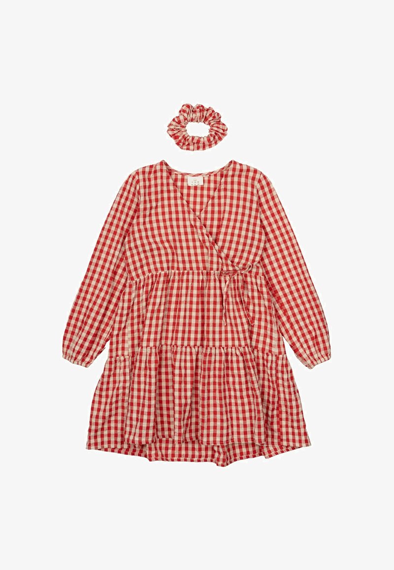 Robe en vichy rouge et blanc avec des manches longues, design d'enveloppement, ourlet à volants et chouchou assorti. Fabriquée en tissu léger.