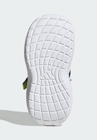 Shoe sole with textured white rubber, featuring a diamond pattern and a smooth edge. Includes a small green accent.