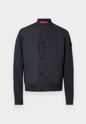 Μαύρο μπουφάν bomber με συνδυασμό απαλού υφάσματος και πλεκτά μανίκια με υφή, με όρθιο γιακά και έξι κουμπιά κλεισίματος.