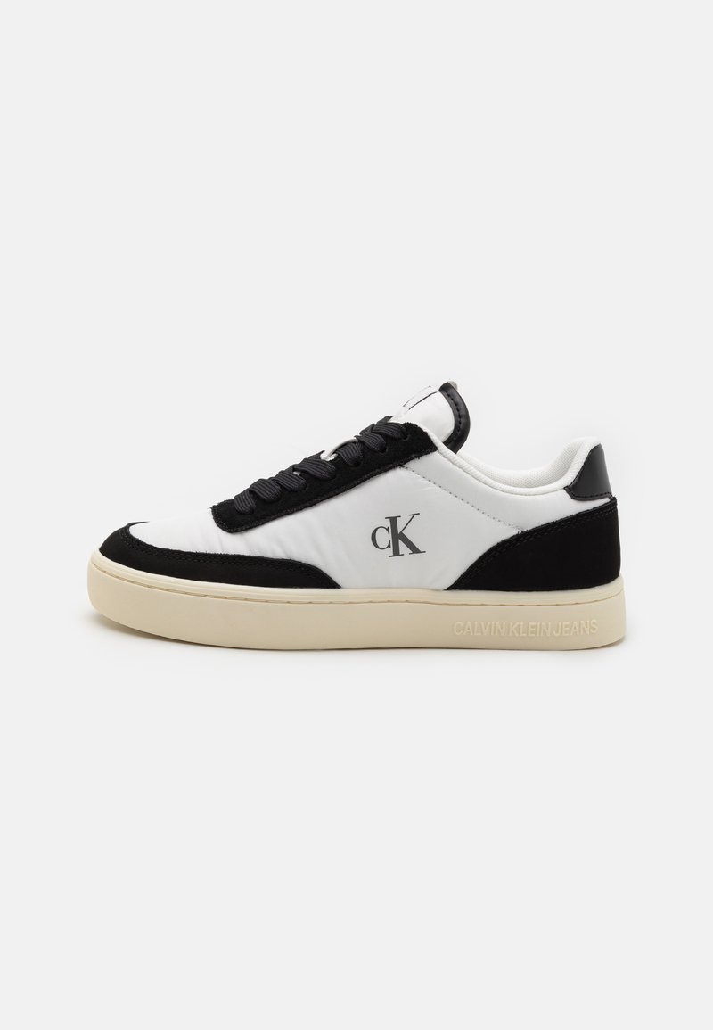 Fekete-fehér sneaker sima bőr felsőrésszel, velúr kiegészítőkkel, tónusos fűzőkkel és krémszínű gumitalppal. Az oldalon logo található.