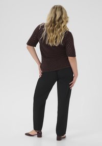 Brown textured knitted top with short sleeves, paired with black straight-leg pants and burgundy flat shoes. Back view of outfit.