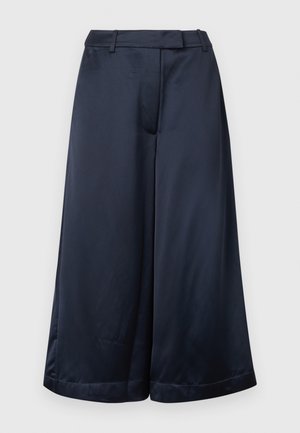Pantalon large bleu marine, coupé court, avec passants de ceinture, fermeture éclair à l'avant, et finition satinée lisse, sur un fond clair uni.