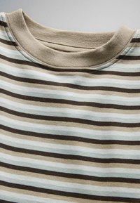 Közelkép egy bézs, fehér és sötétbarna vízszintes csíkos, kerek nyakú póló anyagáról.