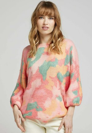 Pull en tricot rose doux avec des motifs abstraits verts et orange. Présente une coupe décontractée avec des manches bouffantes et un col rond.