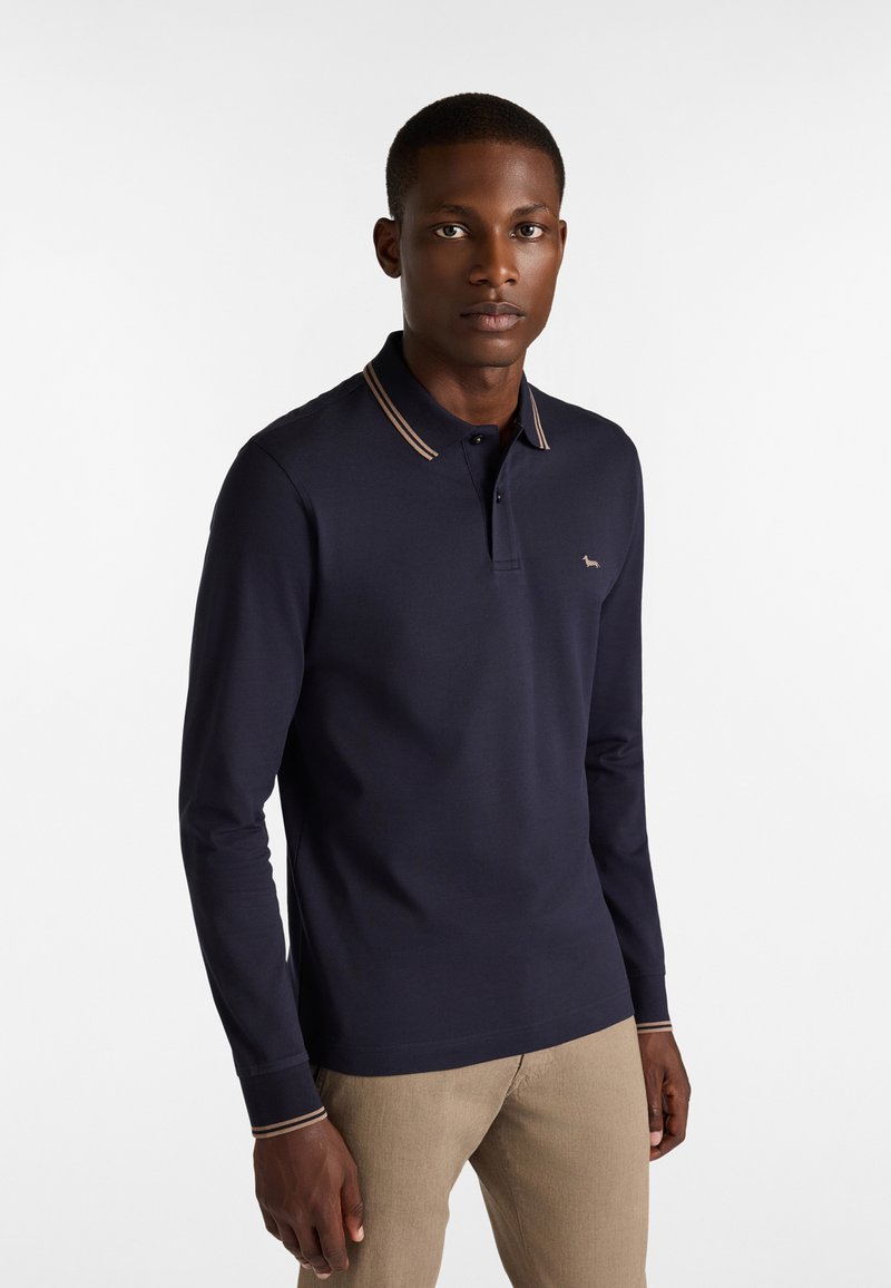 Marineblaues Langarm-Polo mit kontrastierendem beigen Kragen und Bündchen. Mit kleinem Logo auf der linken Brust. Hergestellt aus glattem, dehnbarem Stoff.