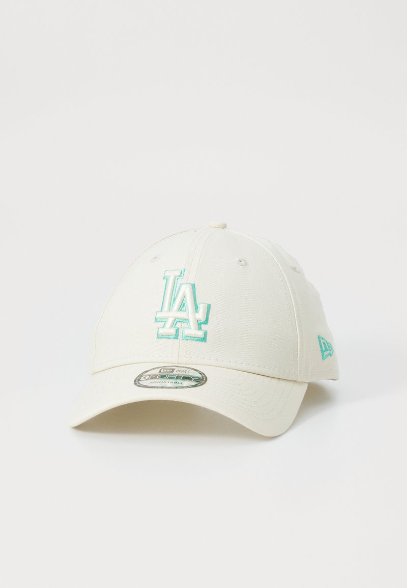 Cream-colored baseball cap featuring an embroidered turquoise "LA" logo on the front and a small logo accent on the side.