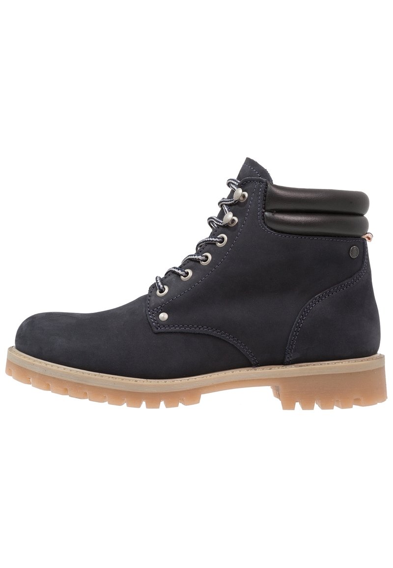 Botines de ante azul marino con suela de goma marrón, que presentan ojales de metal plateado, cordones grises y un cuello acolchado negro.