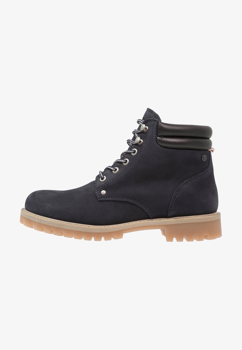 Botines de ante azul marino con suela de goma marrón, que presentan ojales de metal plateado, cordones grises y un cuello acolchado negro.