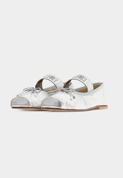 Ασημί μπαλαρίνες με επίπεδη σόλα, γκρι φιόγκους, ανοιχτές μύτες και λευκές ελαστικές λουρίδες με εκτυπωμένους μαύρους αριθμούς και σύμβολα.