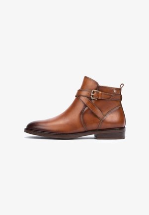 Brown leather ankle boot with a rounded toe, low wooden heel, and decorative strap with buckle detail. Smooth texture and minimal stitching.
