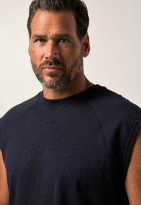 Granatowa bezrękawnik z okrągłym dekoltem i żebrowanym kołnierzem. Miękka tkanina i widoczne szwy na ramionach i bokach.